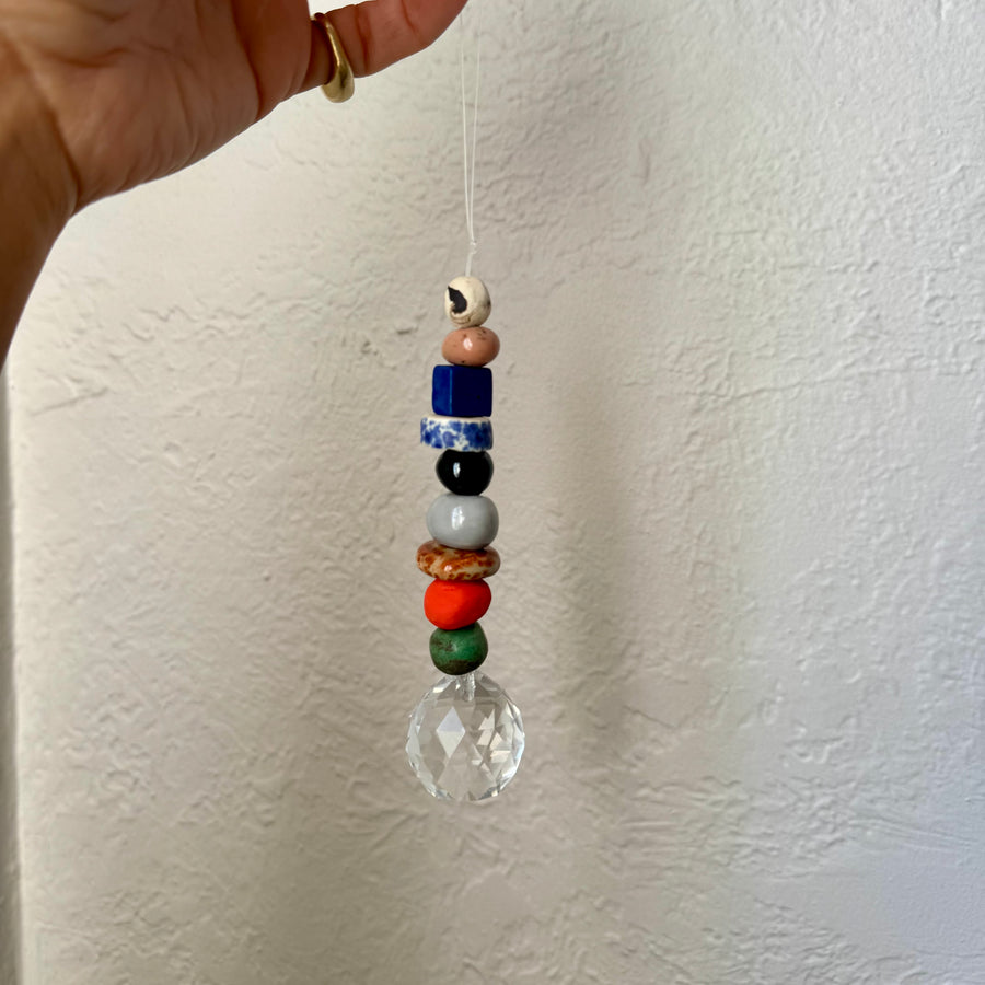 Colorful beaded hanging ornament with a clear crystal ball against a white background