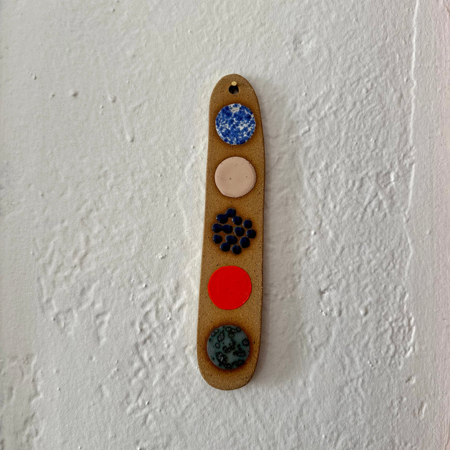 Decorative item with colored circles on a beige ceramic background against a white wall